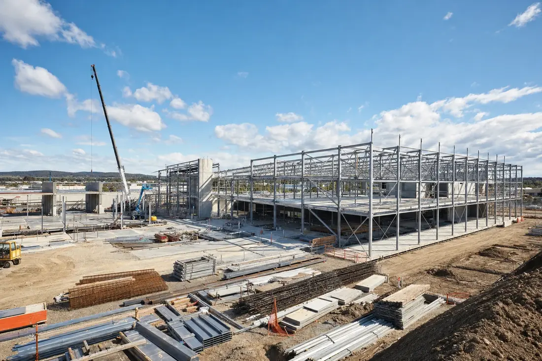 Large commercial construction site with steel frame, concrete slabs and material laydown areas