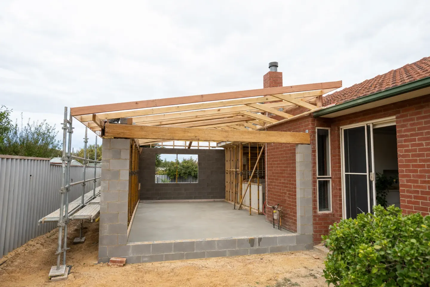 Single storey rear extension under construction on a red brick Perth home with new framing meeting the existing house