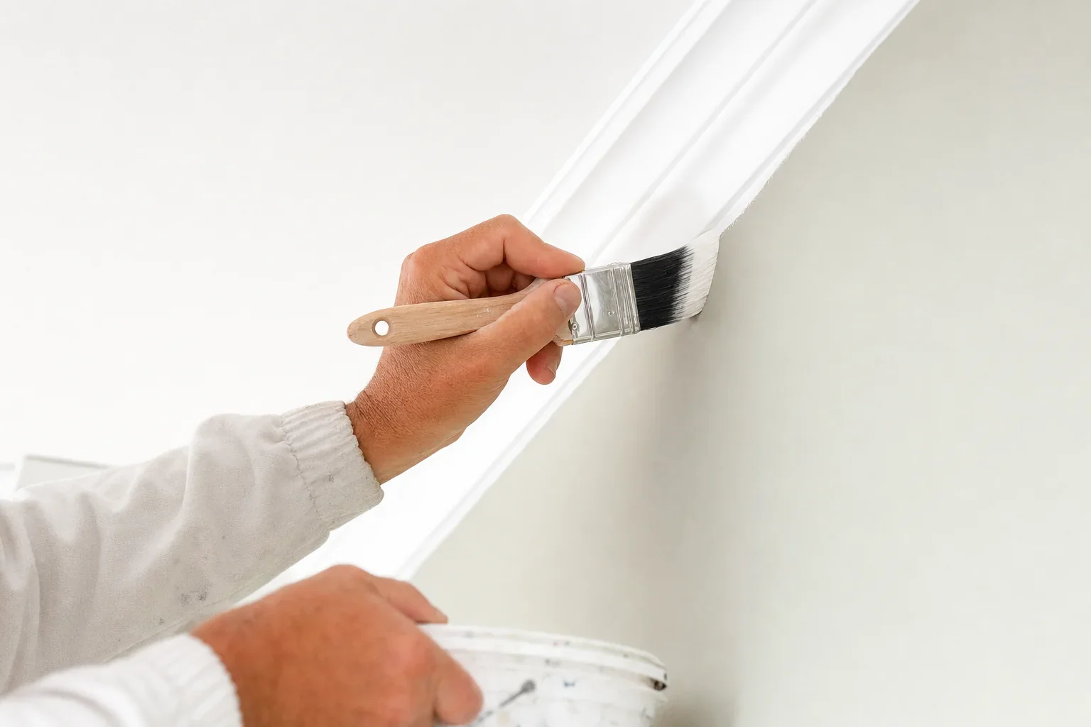 Painter cutting in a clean line with a brush where the wall meets the ceiling cornice