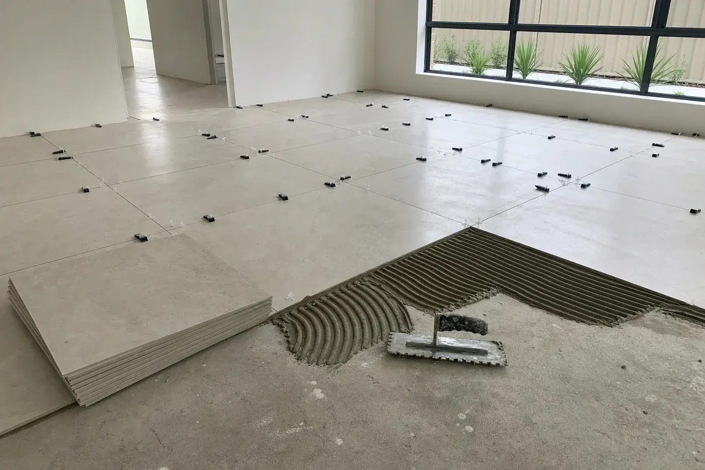 Large format porcelain floor tiles being set out over a screeded floor in a new Perth home