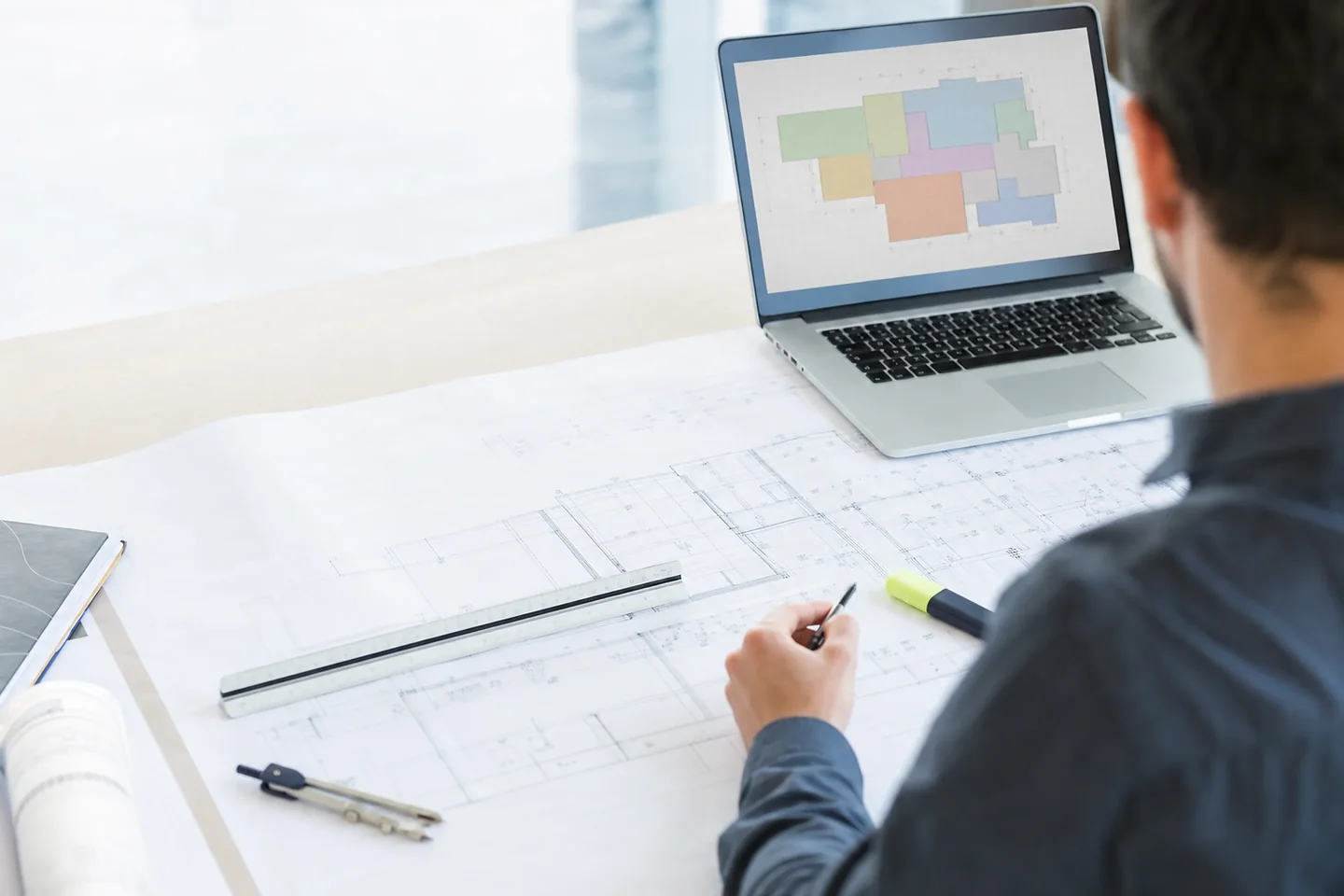 Construction drawings, scale rule and dividers laid out on an estimator's desk in Perth