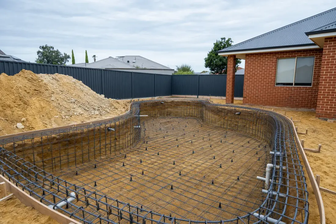 Swimming pool under construction in a Perth backyard with the shell excavated and reinforcement tied