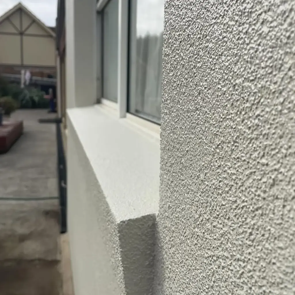 Close view of a textured render finish running across a wall and around a window reveal on a Perth home